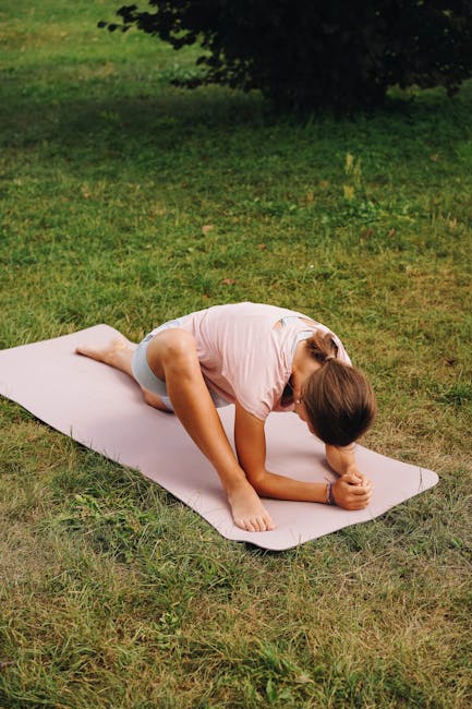 A person gently stretching their back on a yoga mat outdoors